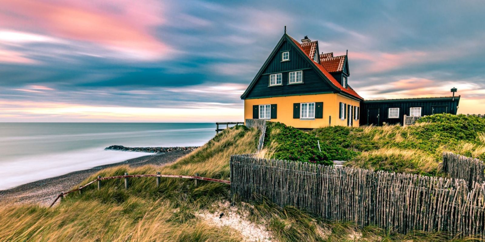Sunset over the dunes and seaside cottages along the coast of Skagen, Denmark.